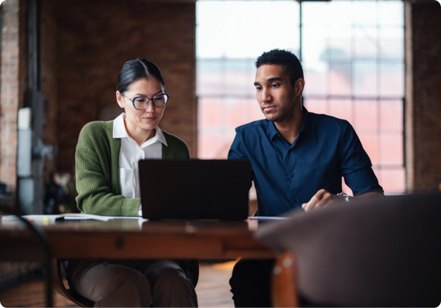Two colleagues collaborating on a project, looking at laptop screen.