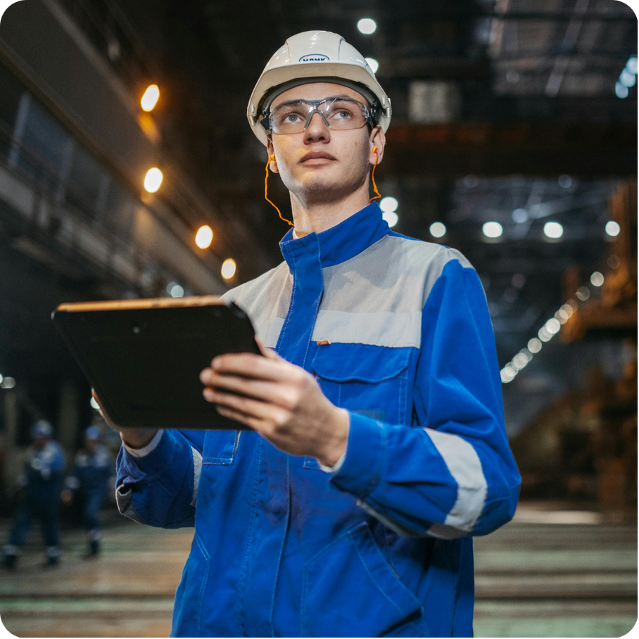 Professional standing in manufacturing setting.