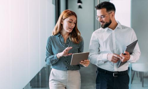 Two professionals walking in an office setting.