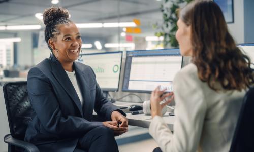 Two professionals talking in an office setting.
