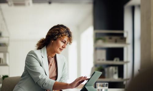 Professional looking at laptop in office setting.