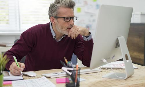 Professional looking at computer monitor in office setting.